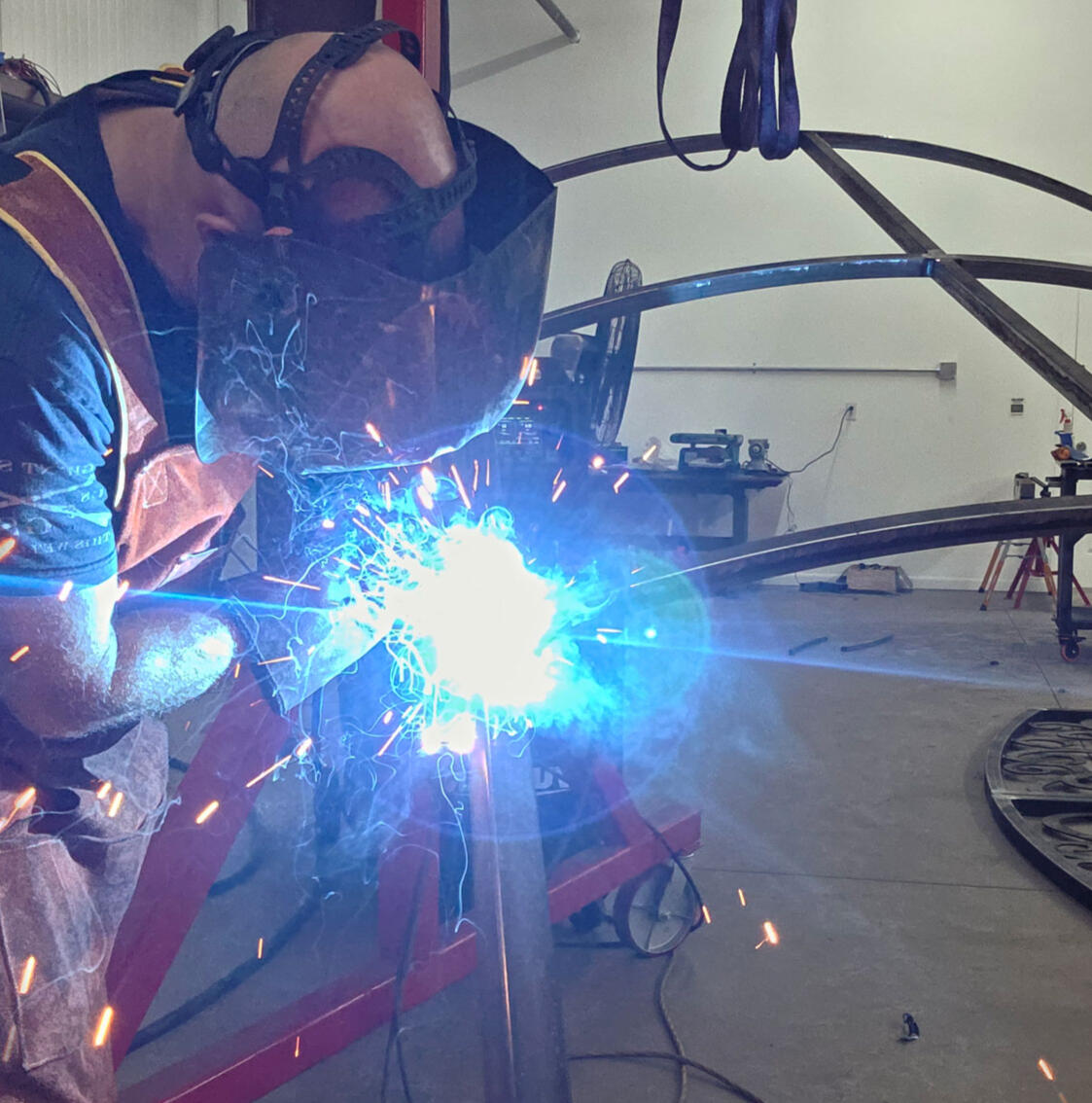 Jason Pedersen welding a custom metal frame at Titan Forge LLC in Springville, Utah, showcasing precision MIG welding and expert metal fabrication.